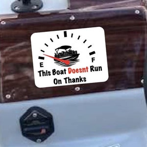 May include: A white boat dashboard with a brown woodgrain panel. The panel has several gauges, including a fuel gauge that reads "This Boat Doesn't Run On Thanks".