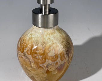 Dispensador artístico de jabón espumoso con bomba, en un esmalte macrocristalino de tonos que van del trigo al caramelo.