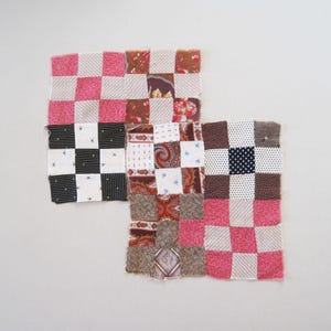 May include: Three small, square patchwork quilt blocks. Each block is made of various fabrics in shades of pink, brown, black, and white. The blocks are arranged in a checkerboard pattern, with each square measuring approximately 2-3 inches.