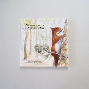May include: A square book titled "Northumbrian Nature Diary" with a watercolor illustration of a red squirrel climbing a tree. The cover also includes text indicating the author and illustrator.
