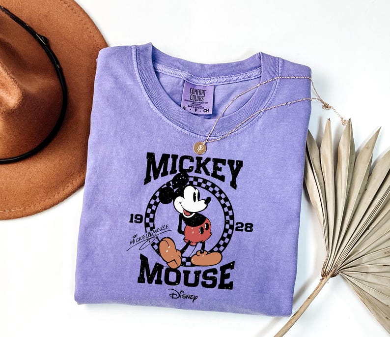 a purple mickey mouse shirt next to a straw hat