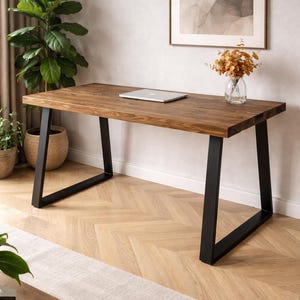 May include: A rectangular desk featuring a thick, dark brown wooden top with a visible grain pattern. The desk is supported by two sturdy, black metal legs shaped in an open trapezoidal frame, providing a stable base for the flat, horizontal surface.