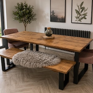 May include: A wooden dining table with a matching bench and two upholstered chairs. The table has a dark wood finish and black metal legs. A decorative fur rug sits on the bench. Two framed pictures hang on the wall.