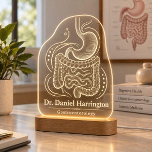 May include: An illuminated acrylic sign featuring an etched anatomical illustration of the human digestive system, including the stomach and intestines. The text reads Dr. Daniel Harrington and Gastroenterology, set on a wooden base.