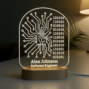 May include: A personalized LED night light featuring a circuit board design with binary code and the name "Alex Johnson" and the title "Software Engineer." The light is set on a wooden base.