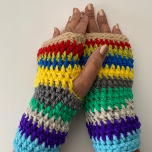 Puede incluir: Un par de guantes sin dedos de crochet coloridos con rayas azules, verdes, amarillas, rojas, grises, moradas y beige.