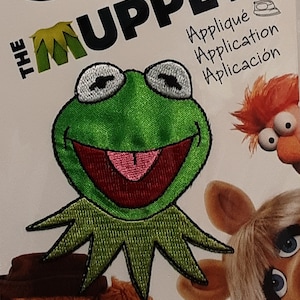 May include: Green felt iron-on patch of Kermit the Frog from The Muppets. The patch features Kermit's face with a big smile and his signature green felt.