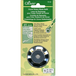 May include: A silver 45 mm wave rotary blade refill for a Clover rotary cutter. The packaging is green and white with text in English, French, German, Spanish, and Dutch. The text reads "Clover Rotary Blade Refill" and "45 mm".