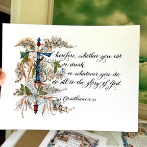 May include: A watercolor painting of a floral design with a calligraphic quote: "Therefore, whether you eat or drink, or whatever you do, do all to the glory of God." 1 Corinthians 10:31.