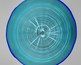 Könnte beinhalten: Eine blaue Glasschüssel mit einem weißen Wirbelmuster. Die Schüssel hat einen blauen Rand und einen klaren Glasboden.