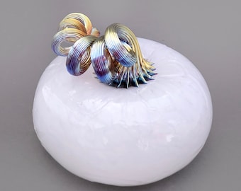 May include: A white ceramic pumpkin with a iridescent, metallic, wire stem. The stem is twisted and curled into a decorative shape.
