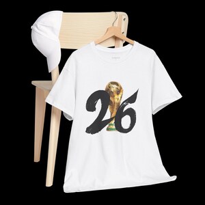 Puede incluir: Camiseta blanca con un gr&aacute;fico negro del n&uacute;mero 26 y un trofeo de f&uacute;tbol dorado. El texto "THREAD" est&aacute; impreso en la camiseta.