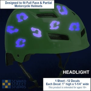 May include: A sheet of 12 glow-in-the-dark helmet decals. Each decal is 1 inch high by 1-1/4 inches wide. The decals are shaped like a leopard print spot and are designed to fit full face and partial motorcycle helmets. The text "HEADLIGHT" is visible in the image. This product is intended for ages 18 and up.