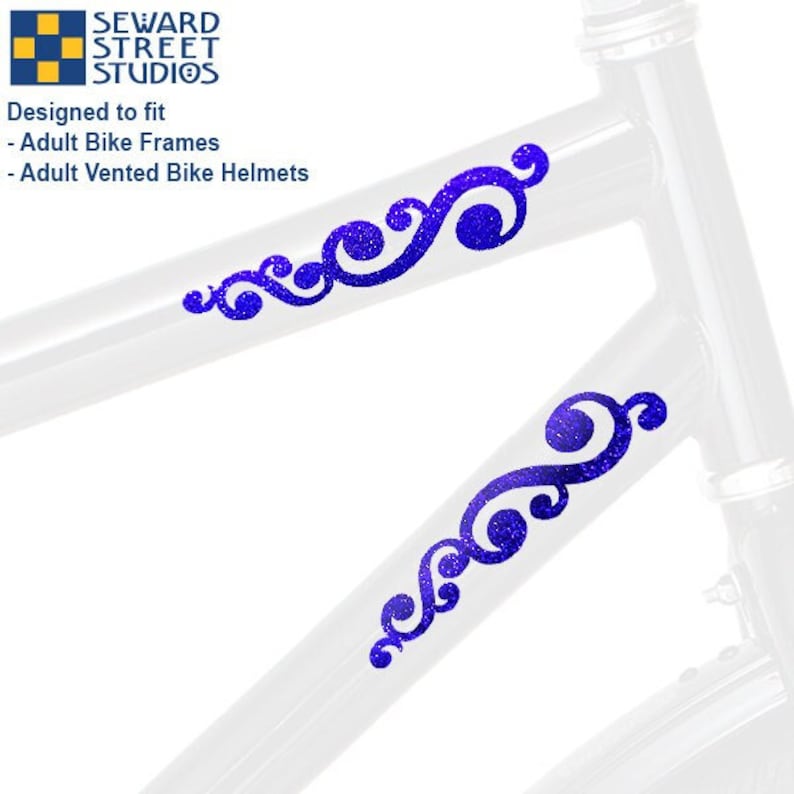 May include: Two blue glittery scrollwork decals applied to a white bicycle frame. The text Seward Street Studios is visible at the top left, along with the text Designed to fit Adult Bike Frames and Adult Vented Bike Helmets.