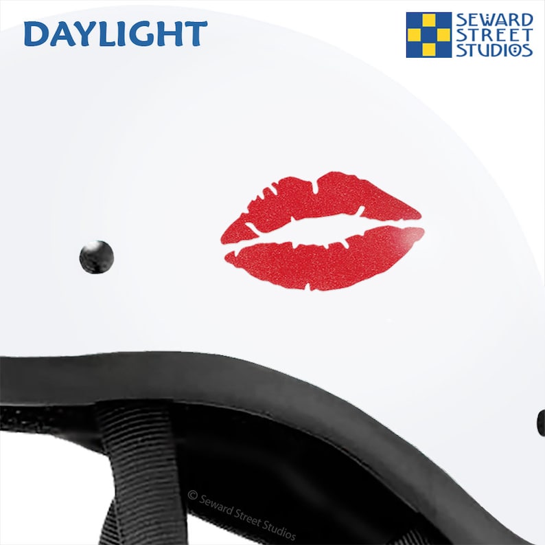 May include: White motorcycle helmet with a red glitter lips decal. The helmet has a black strap and the text "DAYLIGHT" and "Seward Street Studios" are visible.
