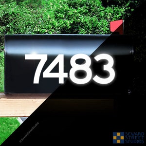 May include: White reflective house numbers 7483 on a black mailbox. The numbers are visible in the dark.