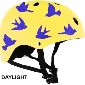 May include: Yellow helmet with blue bird graphics. The helmet has black straps and the word "DAYLIGHT" printed in black at the bottom. This helmet is designed for safety and style.
