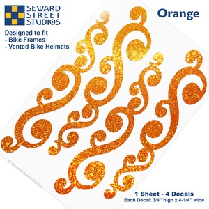 May include: Four orange glitter decals with swirling scroll patterns on a single sheet. Text includes Seward Street Studios, Designed to fit Bike Frames and Vented Bike Helmets, Orange, and 1 Sheet - 4 Decals, Each Decal: 3/4 inches high x 4-1/4 inches wide.
