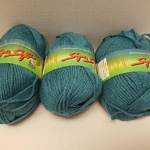 May include: Three skeins of teal blue yarn with the label "Super Soft" printed on each skein.