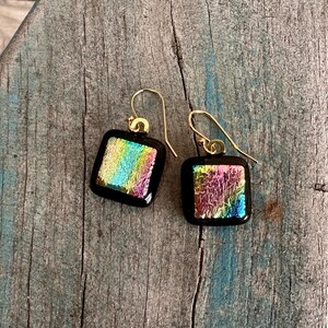 May include: A pair of square iridescent glass earrings with gold hooks. The glass is a mix of pink, blue, green, and yellow.
