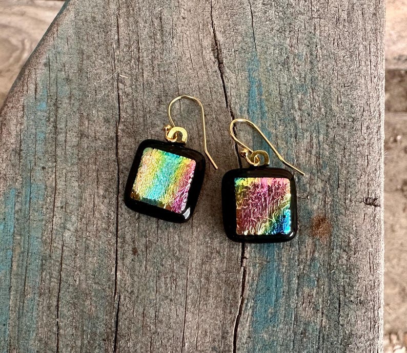 May include: A pair of square iridescent glass earrings with gold hooks. The glass is a mix of pink, blue, green, and yellow.