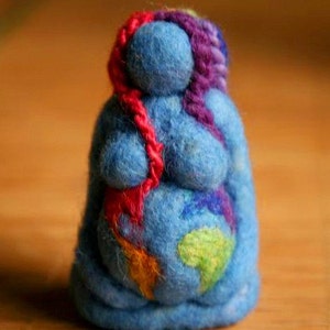 May include: A blue felt doll with a colorful design on its belly. The doll has a red, purple, and pink yarn hair.