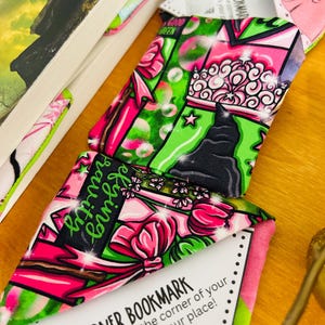 Puede incluir: Marcadores de esquina con vibrantes patrones rosas, verdes y negros, con dise&ntilde;os florales y gr&aacute;ficos. Un marcador muestra el texto "defying gravity" y otro lee "Good Green". Los marcadores est&aacute;n dise&ntilde;ados para deslizarse sobre la esquina de las p&aacute;ginas de un libro.