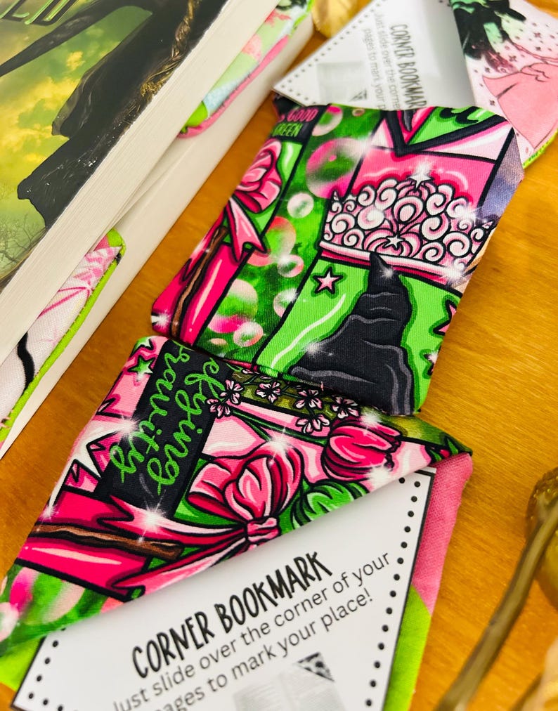 Puede incluir: Marcadores de esquina con vibrantes patrones rosas, verdes y negros, con dise&ntilde;os florales y gr&aacute;ficos. Un marcador muestra el texto "defying gravity" y otro lee "Good Green". Los marcadores est&aacute;n dise&ntilde;ados para deslizarse sobre la esquina de las p&aacute;ginas de un libro.