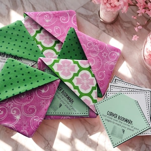 Puede incluir: Un conjunto de marcap&aacute;ginas de esquina hechos a mano con patrones florales y de lunares en rosa y verde. Los marcap&aacute;ginas tienen el texto "CORNER BOOKMARK" en peque&ntilde;as tarjetas. Dise&ntilde;ados para deslizarse sobre la esquina de una p&aacute;gina.