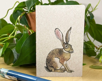 Mini notebook with jackrabbit on cover, pocket in back, and 48 lightly gridded pages. All recycled. Hand sewn with linen thread.