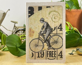 Mini notebook with bicycle collage on cover, pocket in back, and 48 lightly gridded pages. All recycled. Hand sewn with linen thread.