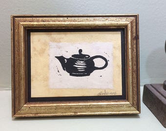 Linocut print of a teapot on tea-stained paper. Small framed art, sealed with acrylic in vintage frame.