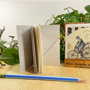 Mini cahier avec collage de bicyclettes sur la couverture, poche arrière et 48 pages légèrement quadrillées. Le tout recyclé. Cousu à la main avec du fil de lin. image 8