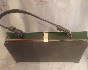 May include: A dark green leather handbag with a gold clasp and a top handle.