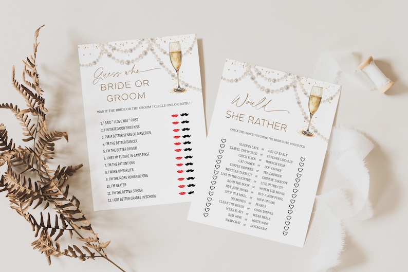 May include: Two white cards with gold text and illustrations for a bridal shower game. One card says "Guess Who Bride or Groom" and the other says "Would She Rather". Both cards have a champagne glass illustration.