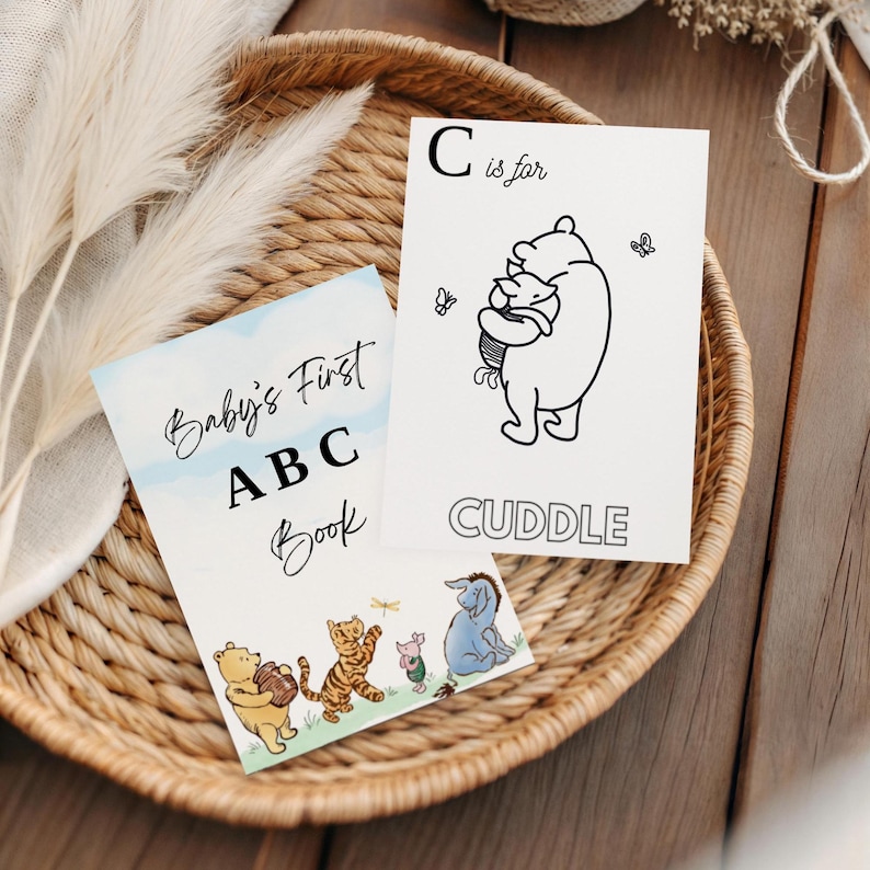 May include: A children's ABC book and flashcards featuring Winnie the Pooh characters. The ABC book reads "Baby's First ABC Book". The flashcard shows Winnie the Pooh hugging Piglet with the word "CUDDLE" below.