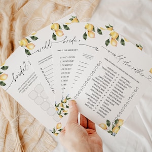 Puede incluir: Un conjunto de tarjetas de juegos para la despedida de soltera con detalles de acuarela de limones. Las tarjetas presentan varios juegos, incluyendo "Bridal", "Wedding Bride" y "Would She Rather". El texto es de estilo manuscrito, con un diseño de rama de limón en las esquinas.