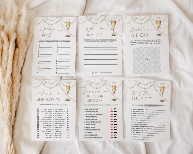 May include: Six bridal shower game cards with champagne glasses and pearl decorations. The cards include games such as "Wedding A-Z", "Who Am I?", and "Bridal Bingo". The design uses a white and gold colour scheme.