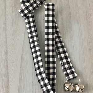 May include: Two black and white gingham ribbon dog leashes with silver bells attached to the ends.