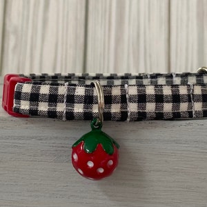 May include: Black and white gingham cat collar with a red and white strawberry charm.