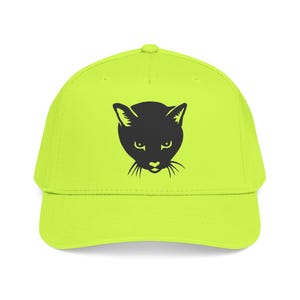 May include: A neon yellow baseball cap featuring a black cat face design. The cat's face is a simple silhouette with pointed ears, eyes, nose, and whiskers. The cap has a curved brim and a button on top.