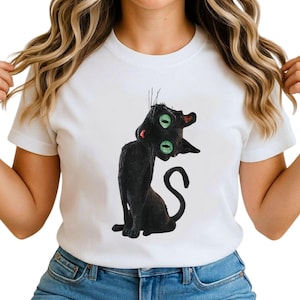 Puede incluir: Camiseta blanca con un gato negro de dos ojos verdes y boca roja. El gato está sentado con la cola enroscada. El diseño está centrado en la camiseta.