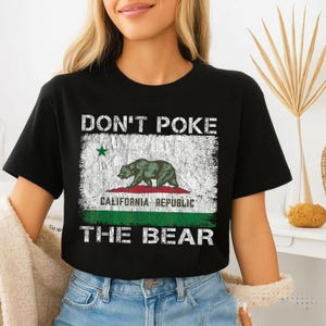 May include: Black t-shirt featuring the California Republic flag with a green bear, a red stripe, and the text "DON'T POKE THE BEAR." The design has a distressed, vintage look.