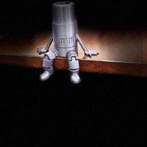 May include: A silver-colored 10mm socket wrench with articulated arms and legs, sitting on a wooden surface.