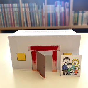 May include: A white paper house with a red door frame and a brown door. A small, rectangular illustration of a family stands in front of the house. The house has a yellow square window.