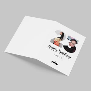 K&ouml;nnte beinhalten: Eine wei&szlig;e, gefaltete Gru&szlig;karte mit der gro&szlig;en Zahl 23, die mit zwei Portr&auml;tfotos gef&uuml;llt ist. Unter der Zahl steht der Text Happy Birthday, der Name AMELIA und eine kleine schwarze Silhouette einer Geburtstagstorte mit Kerzen.
