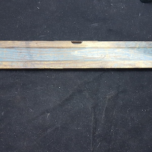 May include: A wooden level with a blue painted center strip. The level is weathered and has a worn finish.