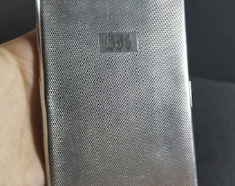May include: Silver cigarette case with a textured surface and the number "236" engraved on the front.