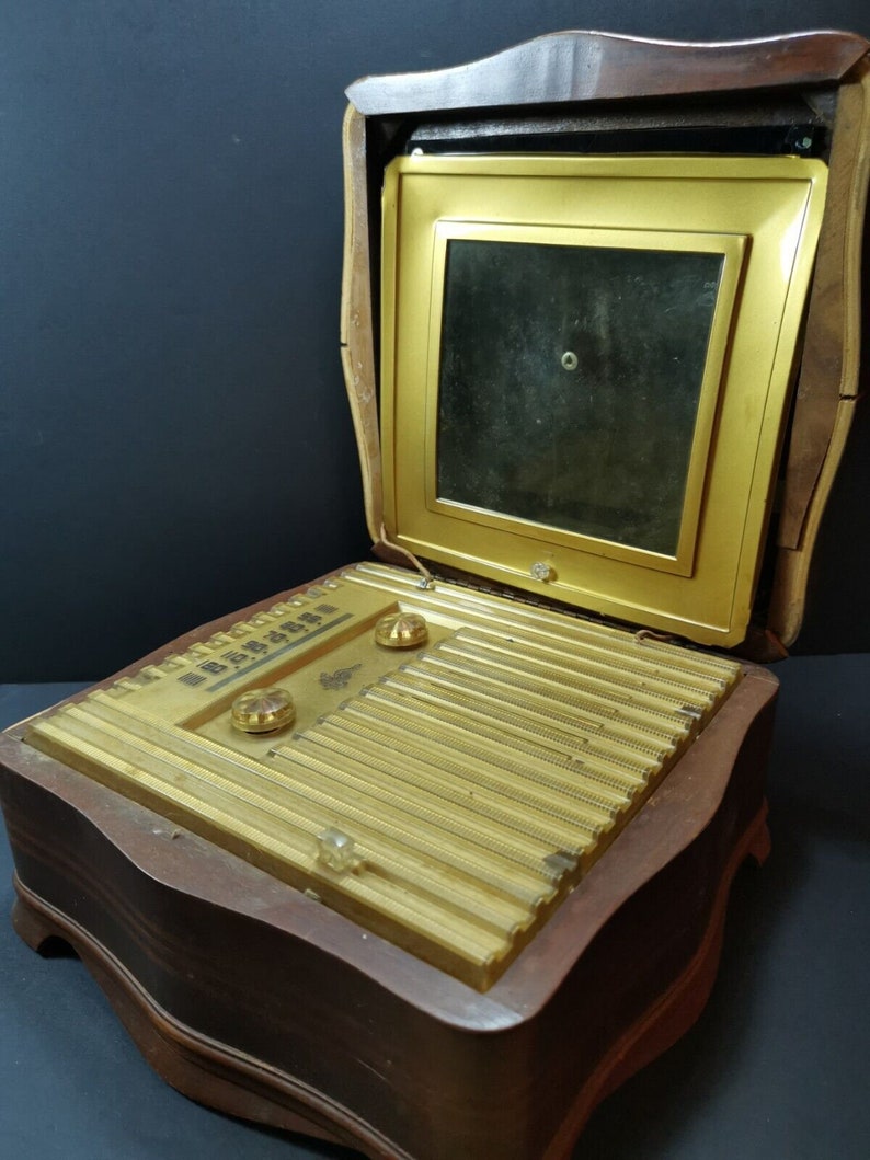 Puede incluir: Una radio vintage de madera con un panel frontal dorado y una peque&ntilde;a pantalla. La radio est&aacute; abierta y la pantalla es visible. La radio tiene un dise&ntilde;o decorativo y est&aacute; en buen estado.