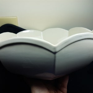 May include: A white ceramic bowl with a scalloped edge. The bowl is large and has a wide, shallow shape.